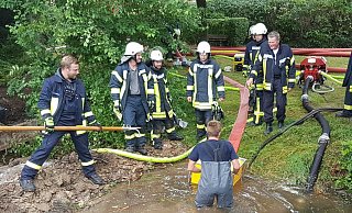 Neben der Rohrbruchstelle wird der Saugkorb der XXL-Pumpe des Hytrans Fire Systems in Stellung gebracht. Im Hintergrund liegen bereits die roten 150 Millimeter messenden F-Schläuche. - Feuerwehr Lichtenau