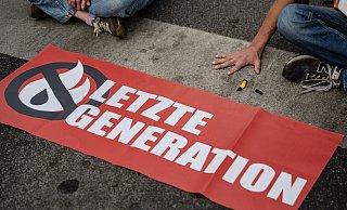Ein Aktivist der Gruppe «Letzte Generation» blockiert eine Kreuzung. - Swen Pförtner/dpa/Symbolbild