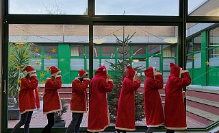 EIn lange Schlange von Nikoläusen spaziert duch das Eingangsfoyer des Gymnasiums aufd er Hüffert. - Hüffertgymnasium