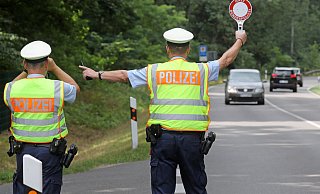 Symbolbild: Zwei Polizisten winken Verkehrsteilnehmer zu einer Kontrolle heraus. - Verwendung weltweit