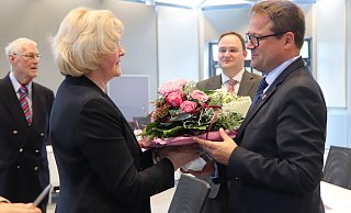 Bürgermeister Lars Bökenkröger gratuliert mit einem Blumenstrauß. Tim Ostermann schaut erst zu und wird dann ebenfalls Blumen überreichen. - Heidi Froreich