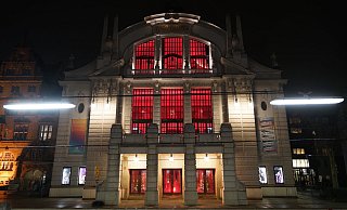 Das Stadttheater ist am Aktionstag der Theater und Orchester von innen rot beleuchtet. „Wir sind da", so die Botschaft.  - Peter Unger