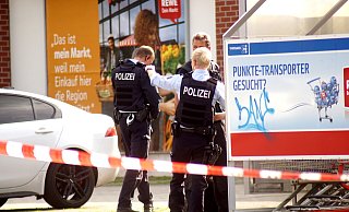 Die Polizeikräfte besprechen den Einsatz vorm Rewe-Markt. - Niklas Krämer