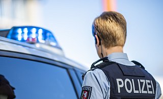 Eine Polizistin steht vor der Kreispolizeibehörde Gütersloh an der Herzebrocker Straße vor einem Streifenwagen. - dpa