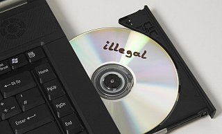 Eine CD mit der Aufschrift "illegal" liegt im CD Laufwerk eines Notebook Computers. - picture alliance/imageBROKER