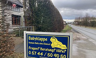 Ein Schild weist an der Hüllhorster Hauptstraße auf den Standort der Babyklappe hin. Der Eingang befindet abgeschirmt von einer hohen Hecke direkt rechts hinter dem Tor am Haus. - Kirsten Tirre