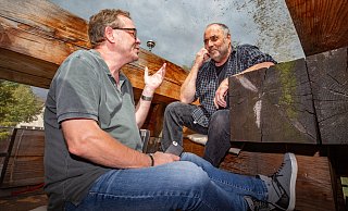 Journalisten unterm Dach: Bernd Kegel, ehemaliger Chef vom Dienst des Bielefelder Stadtblatts, und Stefan Brams, Leiter der NW-Kulturredaktion, beim Mittagsgespräch. Der Dreck, der sich in den Gesichtern spiegelt, liegt auf dem Dach des Holzhauses. - Mike-Dennis Müller / www.mdm.photo