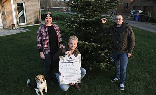 Am Tannenbaum im Vorgarten die Lichter brennen: Sophia Weymann (v. l.), Tristan Wiemers und Dennis Kirchner mit dem Werbeplakat zum „Ossendorfer Weihnachtsbaumverkauf". - Dieter Scholz