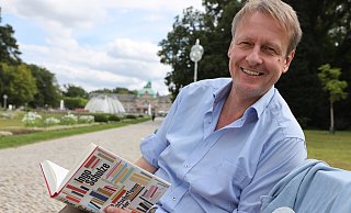 Michael Scholz, Organisator der Poetischen Quellen, mit dem aktuellen Buch von Ingo Schulze im Kurpark Bad Oeynhausen. - Jörg Stuke