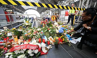 Nach dem Unglück: Eine Frau legt am Gleis 7 des Hauptbahnhofs Blumen ab, im Vordergrund liegt eine Schleife mit der Aufschrift "Frankfurt trauert". - picture alliance