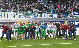 Besondere Beziehung: Trainer Julian Hesse (r.) lobt immer wieder seine Mannschaft des FC Gütersloh für tolle Charaktere und deren Zusammenhalt. Nach dem emotionalen 2:0-Erfolg in Paderborn präsentiert das Team im Moment des Jubels mit den Fans das Trikot des schwer verletzten Kapitäns Björn Rother. - Jens Dünhölter
