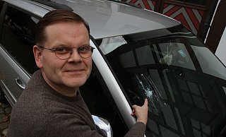 Stephan Aggen zeigt vor seiner Wohnung am Johannisturm auf das Loch in der Windschutzscheibe seines Autos. Er hat es abgeklebt. - Dieter Scholz