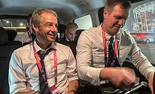 Jürgen Klinsmann (l) sitzt in einem Auto, während er einen Podcast aufnimmt. - Graham Dunbar/AP/dpa