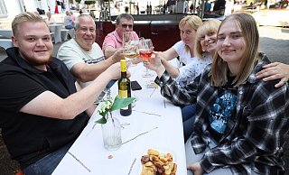 Marvin Niermann (v.l.), Carsten Geisenheiner, Thomas und Anja Stelzer, Eirini Geisenheiner und Laura Bienek haben sich ein schattiges Plätzchen am Stand des Weinguts Weyl gesucht und genießen ihren Wein.Thomas Stelzer bevorzugt - ein bisschen versteckt - ein Bier. - Jörg Stuke
