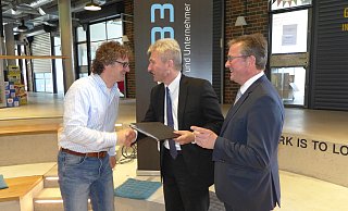 Grund zur Freude: Bürgermeister Michael Dreier (r.) und Uni-Vizepräsident Rüdiger Kabst (l.) erhielten von Minister Andreas Pinkwart den in eine schwarze Kladde verpackten Förderbescheid für Garage 33. - Hans-Hermann Igges