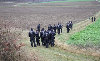 Polizisten duchkämmen den Acker zwischen Warburg und Ossendorf, auf dem der Tote entdeckt worden war. - Dieter Scholz