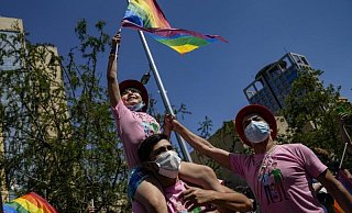 Eine Familie nimmt fahnenschwenkend an der jährlichen Gay Pride Parade in Chiles Hauptstadt teil. - Foto: Esteban Felix/AP/dpa