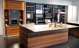 Werkstatt: Eggersmann-Geschäftsführer Michael Wunram hat die Küche in den Arbeitsmodus gebracht. Die Arbeitsplatte ist vom Ceranfeld geschoben, der Vitrinenschrank mit den Backöfen ist geöffnet und in den drehbaren Regalwände ist das Werkzeug des ambitionierten Kochs griffbereit. - Frank-Michael Kiel-Steinkamp