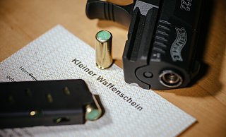 Ein Kleiner Waffenschein liegt zwischen einer Schreckschuss-Pistole "Walther P22", einem Magazin und einer Knallpatrone. - dpa