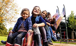 Haben Spaß auf ihrem Nachbarschaftsspielplatz: Greta (3, von vorne), Malina (6), Julia (12), Levi (7) und Ben (7) haben sich fürs Foto auf der mit Graffiti besprayten Rutsche im Flammenstil aufgereiht. Rechts ist ein Teil der Sitzgruppe zu sehen, die im Kreis auf der Mitte des Spielplatzes angeordnet ist. - Susanne Barth