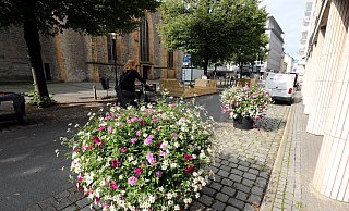 Zwei große Blumenkübel stehen vor der Arkade, die Kicker-Tische sind auf der anderen Seite - vorerst. Dahinter ist eine der Holzsitzmöglichkeiten. - Wolfgang Rudolf