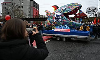 Gießen: Eine Demonstrantin fotografiert einen Motivwagen mit einem Hai mit der Aufschrift "Wir sind mehr!". - Michael Brandt/dpa