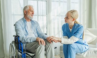 Pflegekraft im Gespräch mit einem Patienten: Frühzeitige Planung erleichtert den Übergang in die Pflege. - picture alliance / Zoonar