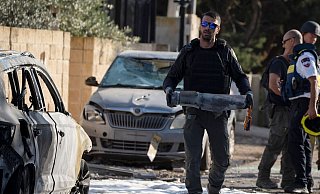 Ein Mitglied der israelischen Sicherheitskräfte trägt ein Stück eines Geschosses, das vom Libanon aus auf Nahariya abgefeuert wurde. - Leo Correa/AP