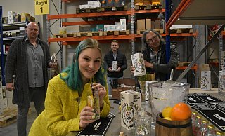 Lara Wenzel, Assistentin des Künstlers, probiert einen Schluck des "Paderborner Dry Hasen Gin". Mike Wolters (v.l.), Vertriebsleiter der "WeiLa" Manufaktur, Frederik Driller, Geschäftsführer von "Getränke Driller", und Künstler Herman Reichold freuen sich darüber, diesen in immer mehr Ladenregalen zu sehen. - Julia Stratmann