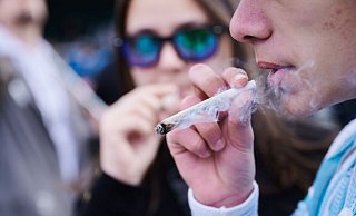 Ein Demonstrant mit einem Joint während einer Demonstration in Berlin für die Freigabe von Cannabis. - Annette Riedl/dpa