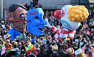Der Mottowagen, der einen entsetzten Clown zeigt, der hinter einer AfD-Maske den noch lebenden Hitler entdeckt, fährt 2024 im Rosenmontagszug durch eine Menschenmenge feiernder Karnevalisten. - Federico Gambarini/dpa