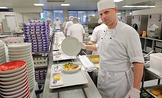 Küchenmeister Peter Thomas schaut sich bei der Endkontrolle jeden Teller, der vom Fließband kommt, an. - Frank-Michael Kiel-Steinkamp