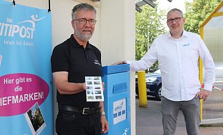 Axel Brinkmann, Inhaber der Edeka-Filiale an der Königstraße (l.), hält die Briefmarken mit den Löhner Motiven in der Hand, die ihm Marco Rabeneick von der Citipost OWL überreicht hat. - Anthea Moschner