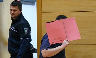 Mit einem Aktendeckel verdeckt der Angeklagte beim Betreten des Gerichtssaals am Landgericht in Bielefeld sein Gesicht. - Andreas Zobe