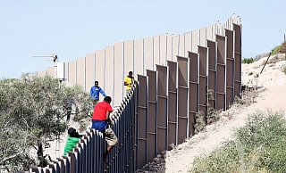 Migranten klettern über einen Zaun auf der italienischen Insel Lampedusa. - Cecilia Fabiano/LaPresse via ZUMA Press/dpa