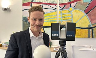 Tim Plumhoff ist inzwischen geschäftsführender Gesellschafter des gleichnamigen Vermessungsbüros in Eidinghausen und steht hier neben einem 3-D-Laserscanner. - Nicole Sielermann