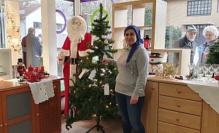 Mitarbeiterin Zanife Güngör steht vor dem Wunschbaum im sozialen Kaufhaus „einLaden“. Güngör trägt nur wegen des Fotos keine Maske. Ansonsten herrscht Maskenpflicht im Sozialkaufhaus, und es wird auf die Einhaltung der vorgeschriebenen Abstände geachtet. - Soziales Kaufhaus "einLaden"
