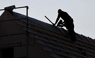 Ein Dachdecker arbeitet auf einem Einfamilienhaus. Das eigene Häuschen bleibt für viele Menschen vorerst ein Traum. - Jan Woitas/dpa