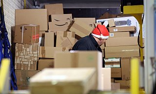 In einer DHL-Zustellbasis wird ein Lkw mit Paketen entladen, um sie auf die Zustellfahrzeuge aufzuteilen. - Bernd Wüstneck/dpa