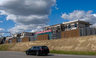 Der Lärmschutzwall an der Jöllenbecker Straße hat nun eine drei Meter hohe Stahlkonstruktion erhalten. Am Ende sollen dort Sträucher und Bodendecker wachsen. Dahinter sind die dreistöckigen Mehrfamilienhäuser des Neubaugebietes erkennbar. - Foto: Andreas Zobe/NW
