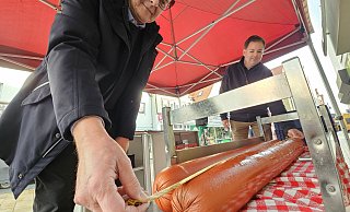 Thomas Holle (links) und Peter Schmüser von Lübbecke Marketing messen stolze 127 Zentimeter bei der Länge der Riesenwürste auf der Bühne am Wappenplatz. - Alexandra Stratmeier