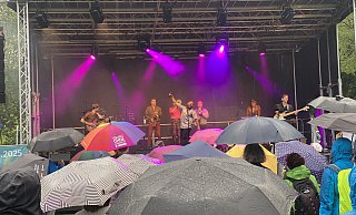 Fatcat-Sänger Kenny Joyner sorgt für Stimmung beim Paderborner Publikum, das mit Regenschirmen bestens gegen das miese Wetter gewappnet ist. - Julia Spiekerkötter
