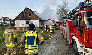 Ein Bagger reißt Teile des unbewohnten Gebäudes ein, damit die Feuerwehr Warburg erfolgreich löschen kann. - Freiwillige Feuerwehr
