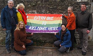 „In unserer Gemeinschaft sind alle willkommen“, signalisieren Pfarrer Marcus Falke-Böhne (r.) und die Pfarrgemeinderatsmitglieder Josef Fuhrmann (v. l.), Elisabeth Seifert, Sandra Gnade, Elisa Fuhrmann und Gemeindereferentin Michaele Grote mit dem Aufhängen der neuen Fahne. - Josef Köhne