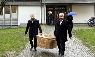 Bürgermeister Thomas Meyer (l.) und Landrat Jürgen Müller tragen den Timpkenkorb durch den Regen zum Kircheneingang. - Lillia Seifert