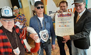 Stilecht mit Rettungsring und fescher Sonnenbrille: Zeremonienmeister Rudi Ryll (v. l.), Titgenbürger 2025 Stefan Bosse. Michael Artus und Präsident Michael Hendker vom Warburger Meister- und Gesellenverein überreichen die Urkunde. - Dieter Scholz