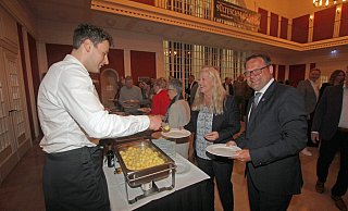 Bürgermeister Lars Bökenkröger (r.) und seine Partnerin Manuela Mundt stehen Schlange für den Grünkohl. Nils Torbrügge (l.), Geschäftsführer von GWD Minden, befüllt die Teller. - Ulf Hanke
