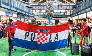 Kroatische Fußballfans posieren im Hamburger Hauptbahnhof mit ihrer Fahne. - Markus Scholz/dpa