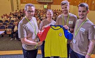 Fast 200 Helferinnen und Helfer haben am Montagabend beim Briefing in Herford ihre Infos für den Einsatz bei der Deutschland Tour erhalten. Frank Hölscher (v.l.), Anna Otte, Lars Sundermann und Christian Forner vom örtlichen Organisationsteam päsentieren das Helfershirt, mit dem alle am Donnerstag ausgestattet werden --- Radsport Vorbereitungen auf die Deutschland Tour in Herford - Foto vom 18.08.2025 - Gunnar Feicht