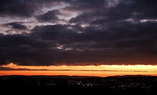 Der Mond blinzelt durch die Wolken, der Stern von Bethlehem leider nicht. Hübsch anzusehen ist der Himmel an diesem Abend trotzdem. Unten sind die Lichter der Stadt zu erkennen. - Meiko Haselhorst